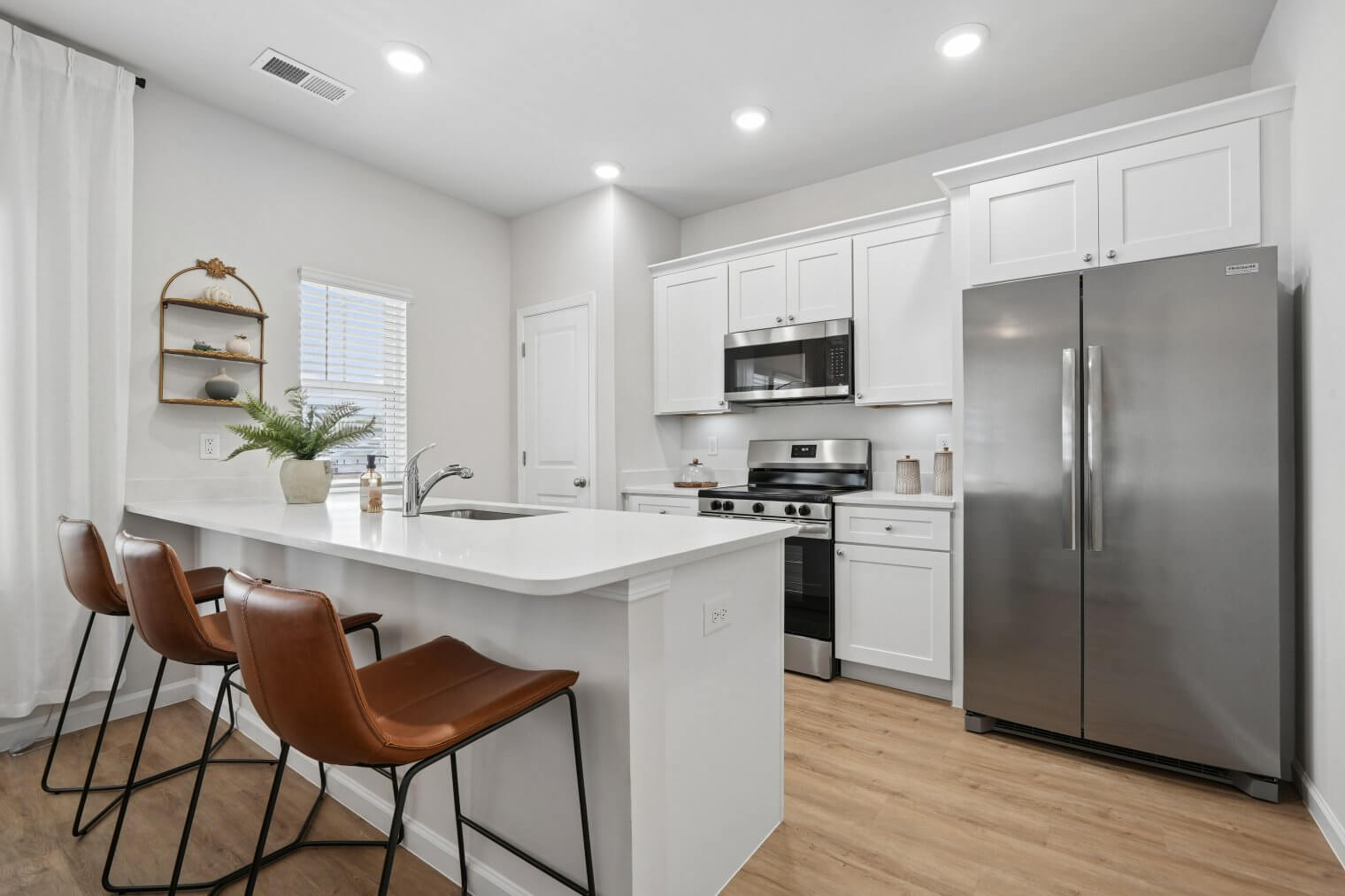 modern kitchen with bar stools white countertops and stainless steel appliances